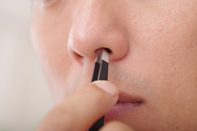 毛抜きで鼻毛の処理をする男性