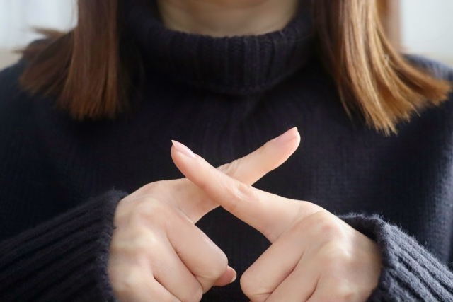 指でバツを作る女性